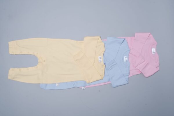 A pink, blue, and yellow baby suits laying on a grey surface.