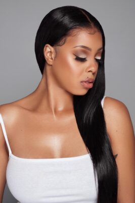 A black woman wearing a white top and long black hair.